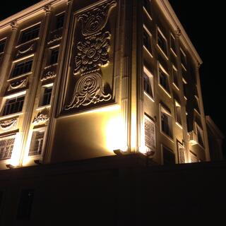 Floodlights highlight window surrounds, but cast windows into darkness.