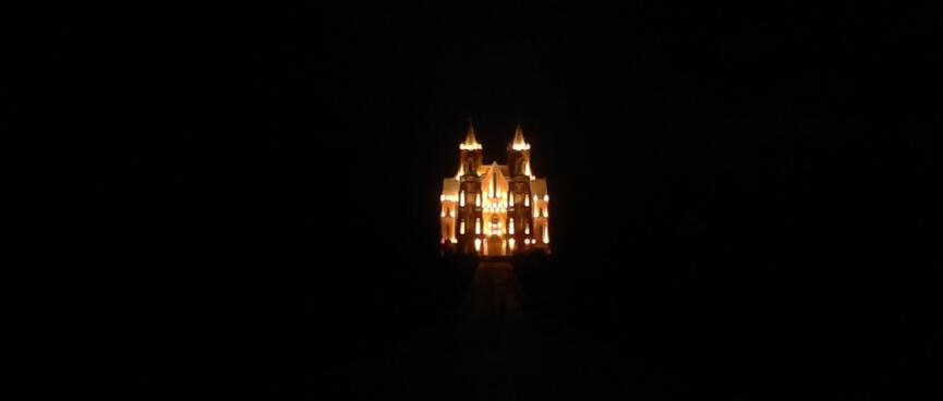 A church with two towers stands bright against the dark night sky.