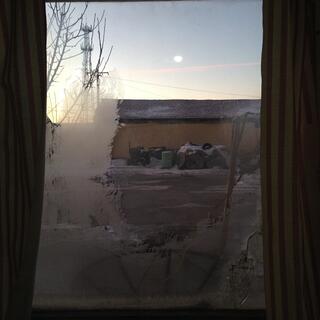 There is ice on the window, through which I can see blue sky and a tractor.