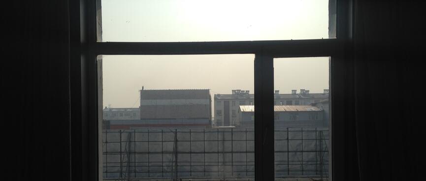 The blue sky above buildings has a thick yellow tinge.