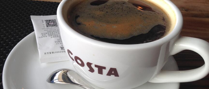 A coffee cup sitting on the edge of a saucer.