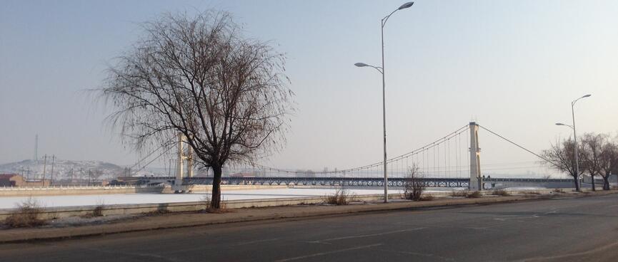 A suspension bridge crosses a frozen river.