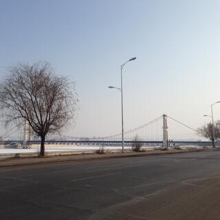 A suspension bridge crosses a frozen river.