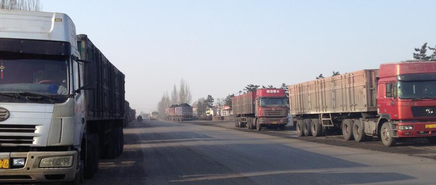 Big trucks line each side of the road.