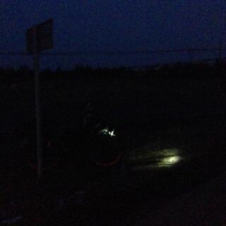 Night scene with an inky blue horizon and the beam from my bikeʼs front light.