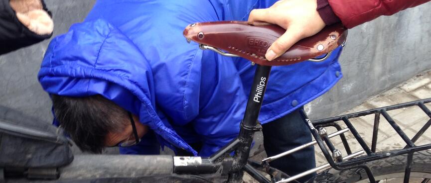 A man in a blue puffer jacket bends down behind my bicycle.