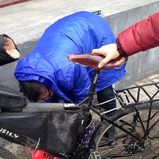 A man in a blue puffer jacket bends down behind my bicycle.
