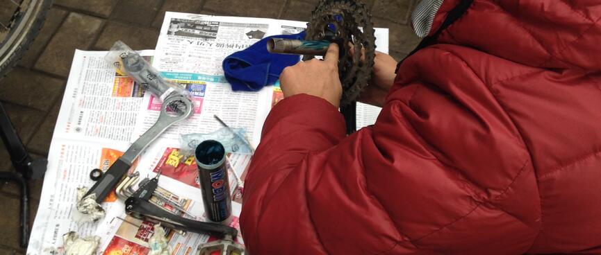 A man in a red jacket smears grease on the crank spindle.