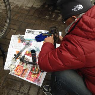 A man in a red jacket smears grease on the crank spindle.