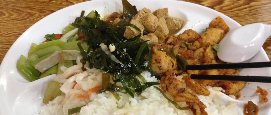 A plate containing rice, chicken, vegetables and salad.