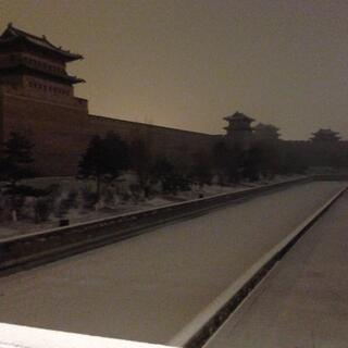 Snow filled moat and tall walls with turrets.