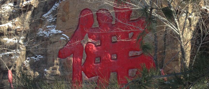Large red Chinese glyphs etched into a rock wall.