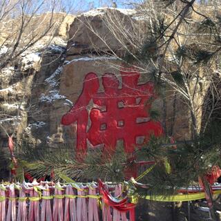 Large red Chinese glyphs etched into a rock wall.