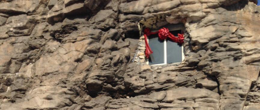 An aluminium framed window high up in a rock wall.