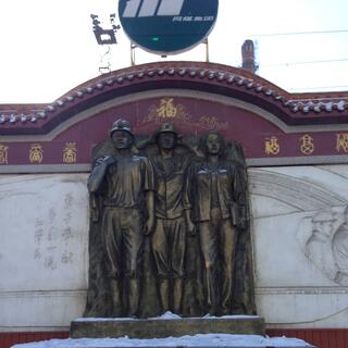 A life-size metal monument features two male miners in hardhats and a woman.