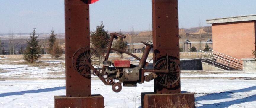 A rusted bike frame attached to a narrow metal arch.