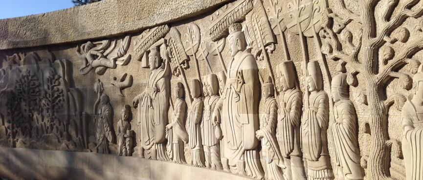 Robed figures carved into a stone wall.