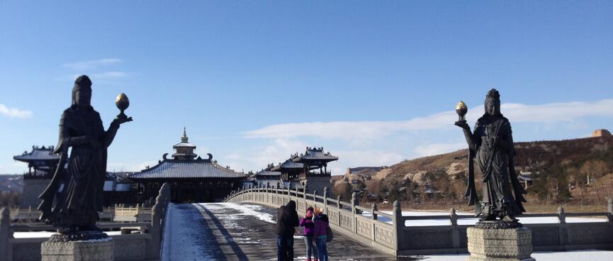 Two tall metal statues of women guard the entrance to a bridge.