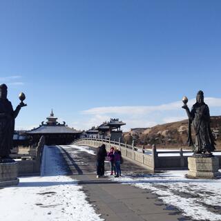 Two tall metal statues of women guard the entrance to a bridge.