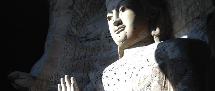 A huge buddha carving bathed in a beam of light.