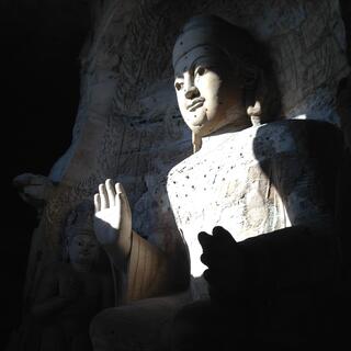 A huge buddha carving bathed in a beam of light.