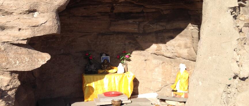 A shallow cave contains a small table covered in a yellow tablecloth.