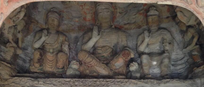 A carving of three people seated on a narrow ledge.