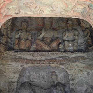 A carving of three people seated on a narrow ledge.