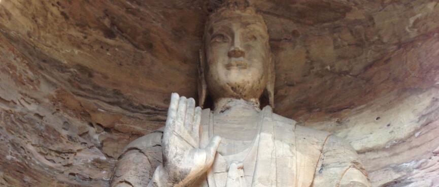 A buddhaʼs carved facial features are wearing away.