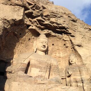 Large and small buddha in a shallow cave.