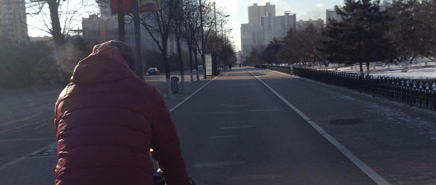 Zhihong rides down a wide empty cycleway