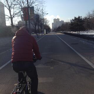 Zhihong rides down a wide empty cycleway