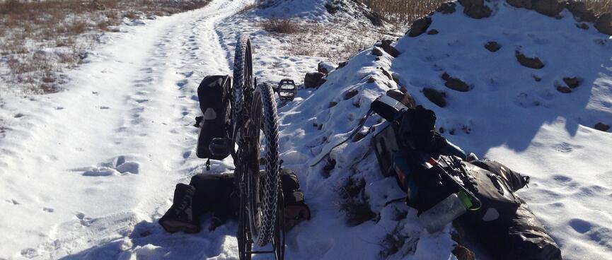 My bike upside down on a snow covered track.