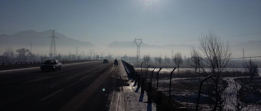 A motor scooter rider wheels his machine along the icy side of the road.