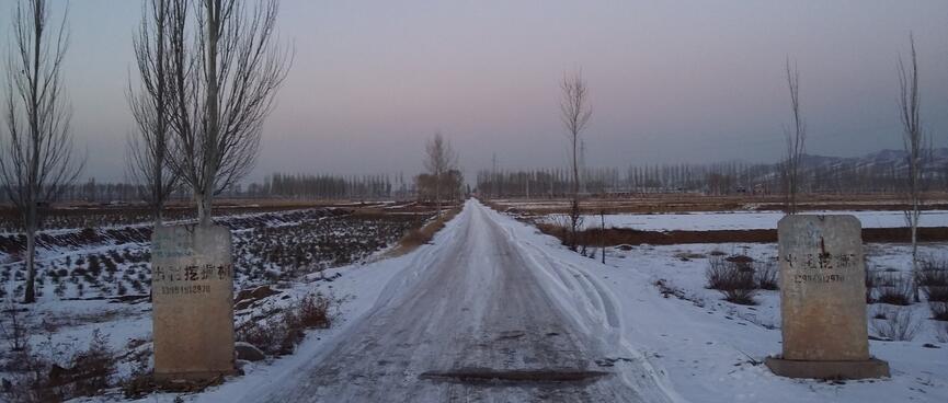 A snowy road extends into a beautiful sunset.