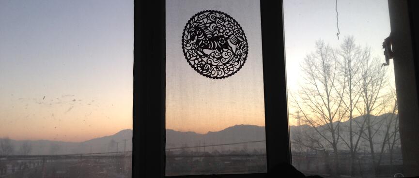 The sky lightens with apricot hues as the sun rises over a long mountain range.