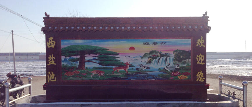 A plaque features a picture of majestic waterfalls, birds, deer and a red sun in a multicoloured pastel sky.