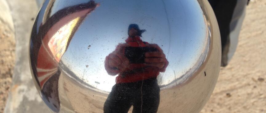 My distorted reflection in a round metal ball.