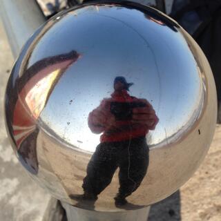 My distorted reflection in a round metal ball.