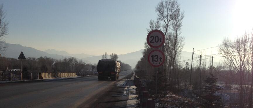 Traffic on a long straight road heading towards mountains.