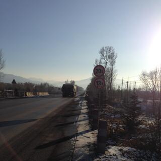 Traffic on a long straight road heading towards mountains.