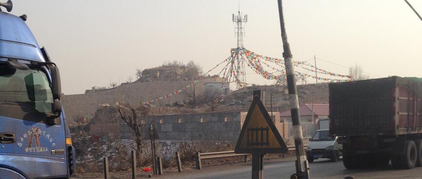 Prayer flags visible in a gap between two trucks.