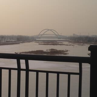 A modern curved bridge as viewed from a more traditional one.