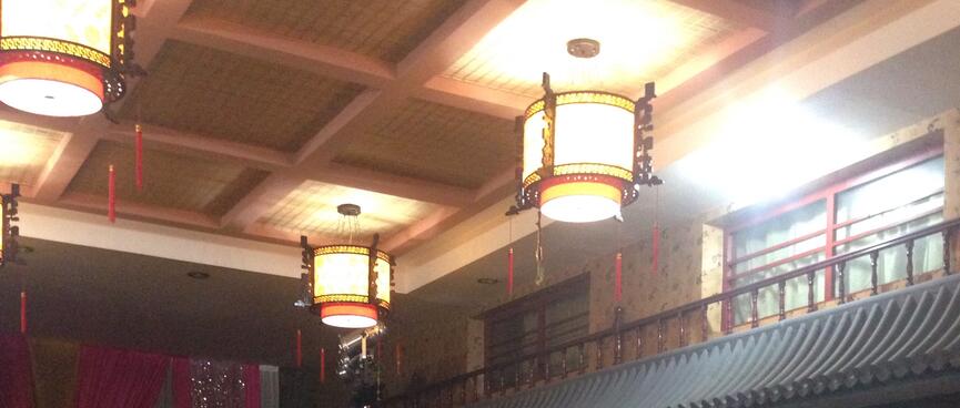 The ceiling of the dining room features ornate round lampshades and a balustrade below internal windows.