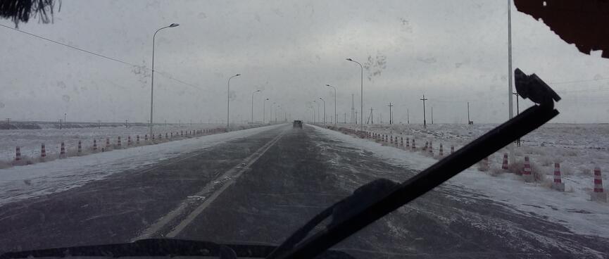 View through the windshield to a snow-lined highway.