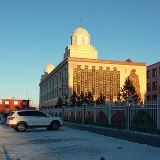 Vertical strips of text on the side of a square building with twin domed towers.