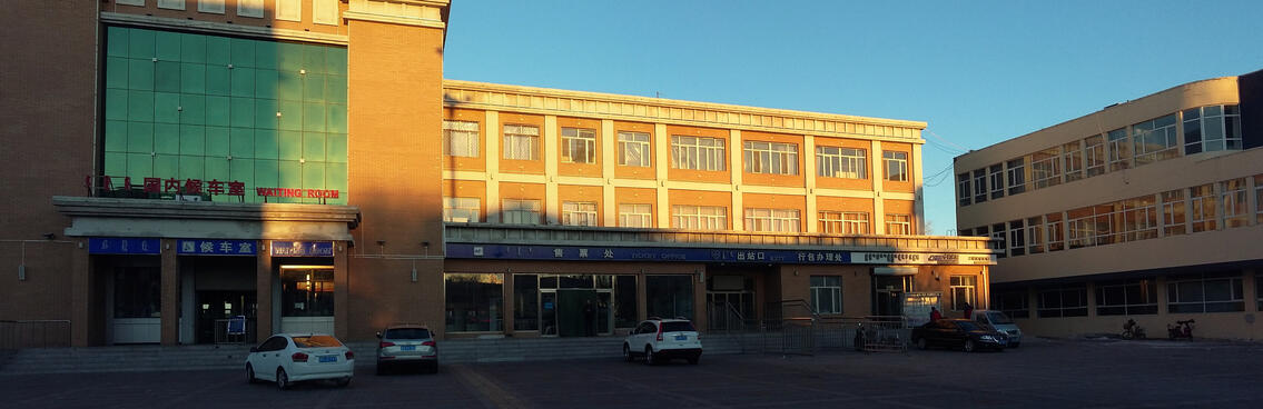 A glass and brick three storey building is illuminated by the sun.