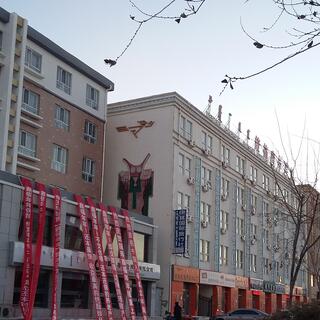 The side of a building features a stylized figure wearing a cloak and a horned mask.