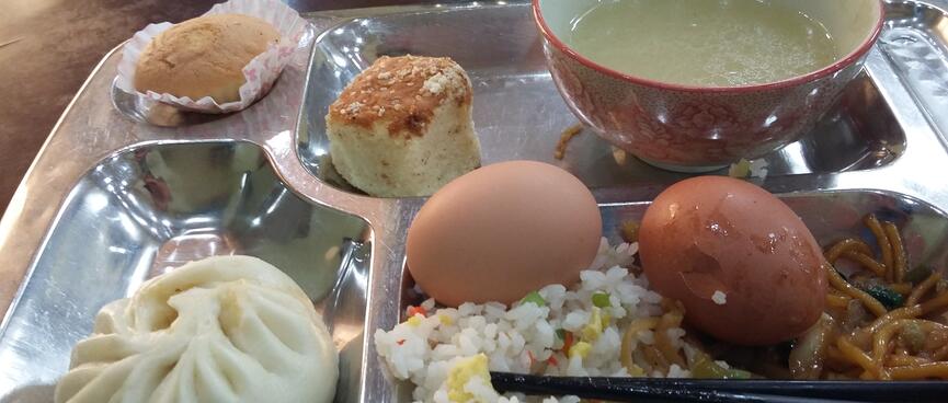 A metal tray with four compartments filled with a variety of foods.