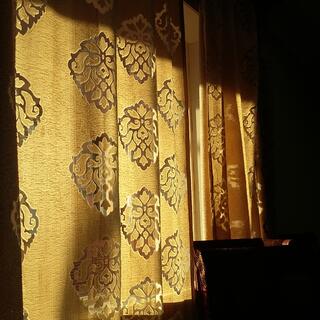 Sunlight illuminates golden curtains adorned with ornate diamond motifs.